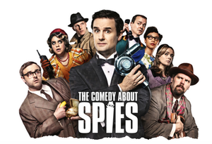 Group of eight people in vintage attire, some with suspicious expressions. Central text reads "The Comedy About Spies."