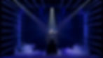 Female singer in a sparkling black gown performs on a dark stage with blue spotlights and fog.