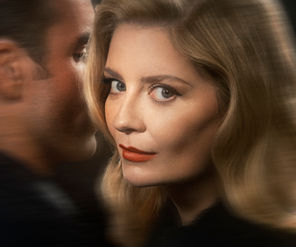 Double Indemnity Play Artwork. A woman with blonde hair and red lipstick looks forward with a serious expression. A man is whispering in her ear. Blurred dark background.