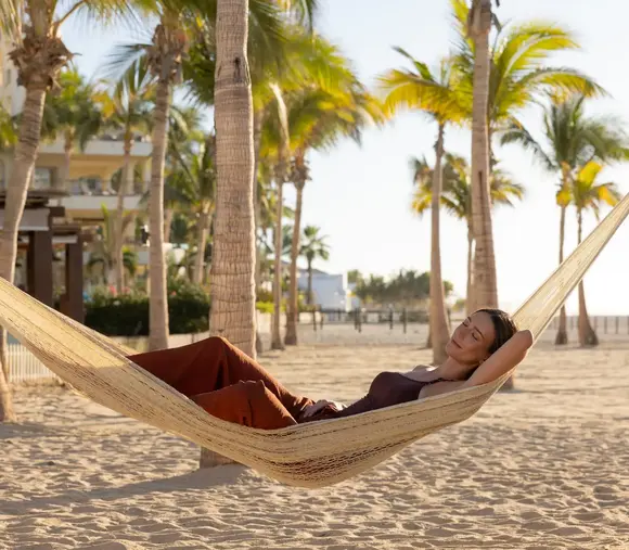 Guest relaxing in a beachfront hammock at Hyatt Ziva Los Cabos