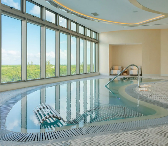 Indoor spa hydrotherapy pool at Hotel Mousai Cancun with floor-to-ceiling windows and jungle views.