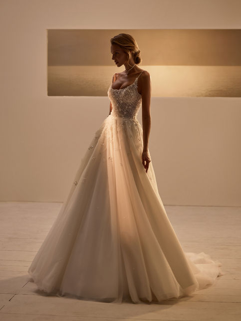 Ler by Luce Sposa: refined A-line wedding gown with thin-strap bodice richly embellished with beads, crystals, pearls, sequins, and voluminous lace flowers; back with zipper and internal lacing; sheen skirt echoing floral and sparkle motifs flowing into a long train