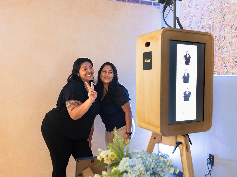 Two A&A Booths team members posing together beside the Wooden Oak Photo Booth at an event.