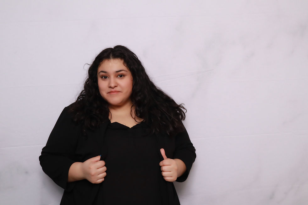 Bryana, A&A Booths lead photographer, posing in a black outfit against a light studio backdrop.