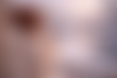 Mujer con suéter crema sostiene una taza de café caliente mientras mira un paisaje de nieve al amanecer desde una ventana.