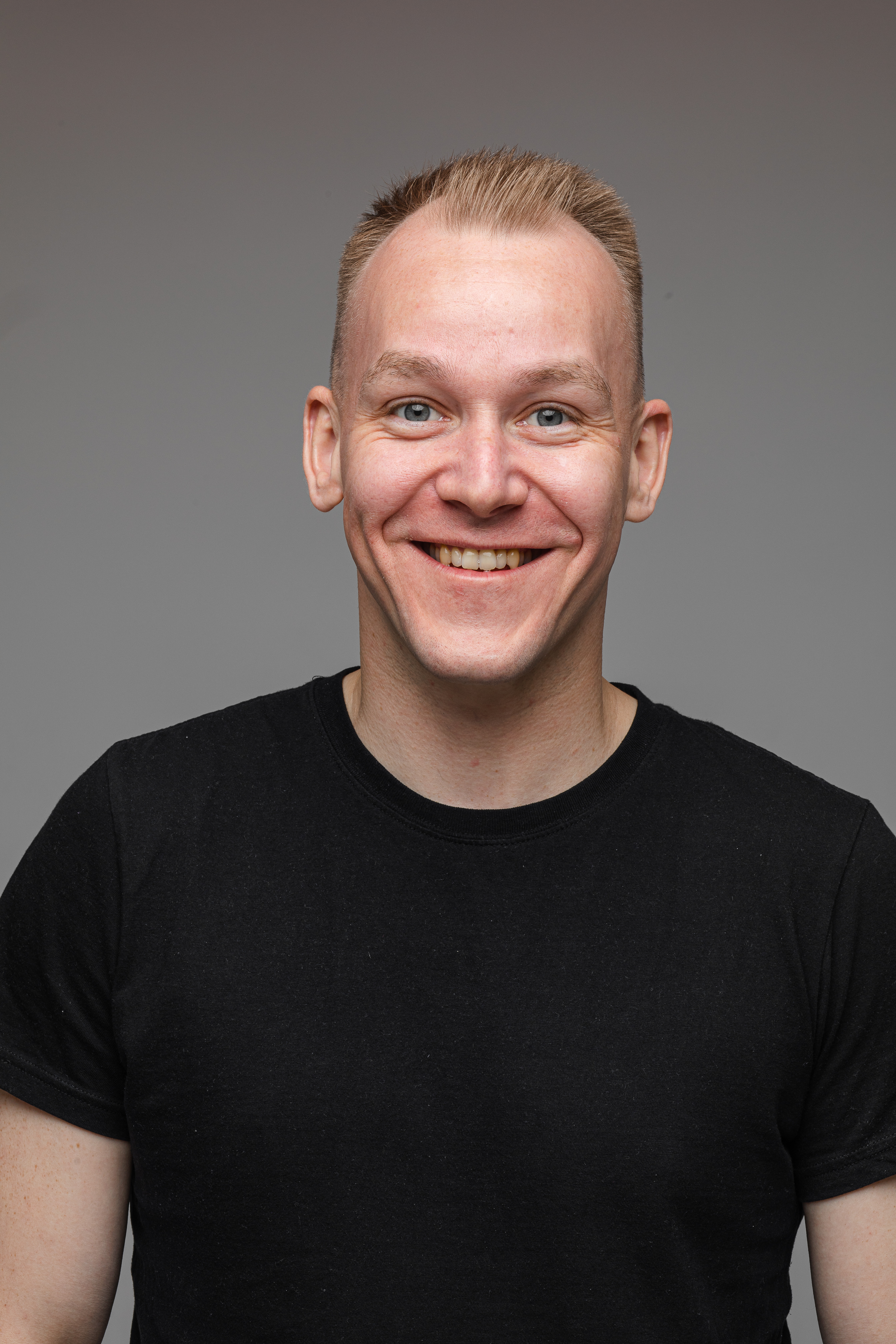 portrait-caucasian-man-black-t-shirt-smiles-isolated-grey-wall.jpg