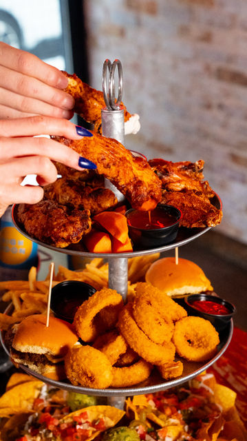 Delicious three-tiered platter: fried chicken, sliders, onion rings, fries, and nachos