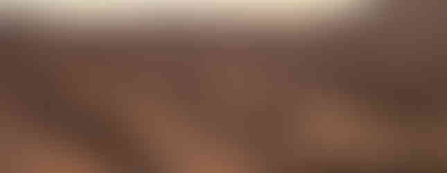 Un groupe de chameaux menés par des cavaliers traverse de vastes dunes de sable doré sous un doux ciel de coucher de soleil dans le désert.