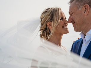man and woman nuzzle noses under veil after deciding on Summer vs Fall Elopements