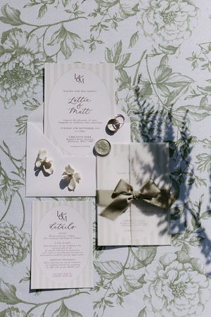 Beautiful wedding invitations in a stripe design in soft sage green, with green silk bow to finish. 

Photo credit: Jade Greenbrook Photography