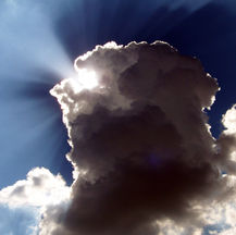 Photograph of the sun breaking through dark clouds