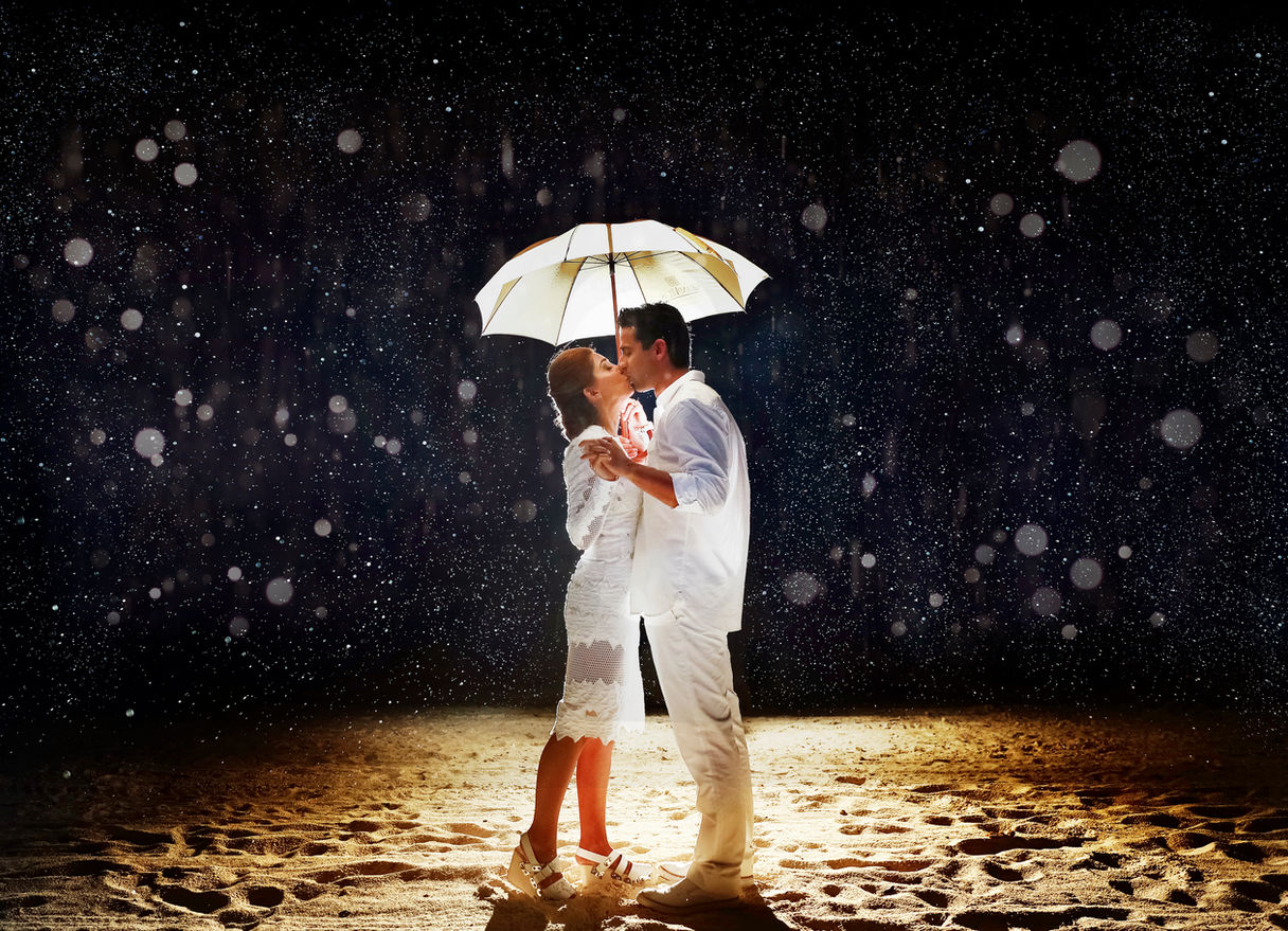 Couple kissing under umbrella on a rainy night, Grand Velas