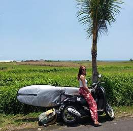 woman riding motorbike with surfboard in a surf trip