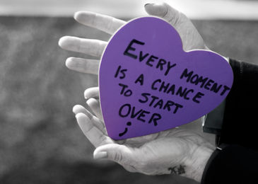 Hands holding purple heart card: "Every moment is a chance to start over"