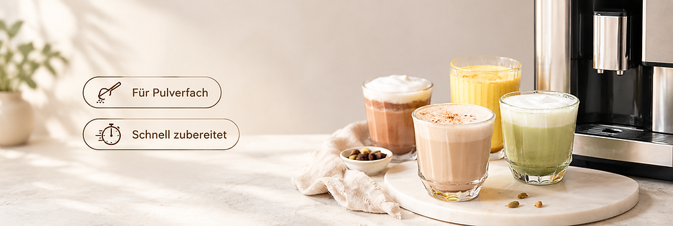 4 Gläser mit unterschiedlichen Heißgetränken stehen auf einem weißen flachen Teller vor einem Kaffeevollautomaten. zu sehen ist ein beiger Chai, ein grüner Matcha, eine gelbe Golden Milk und ein Kakao mit Milchhaube