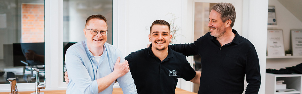 Drei Mitarbeiter lachen in die Kamera