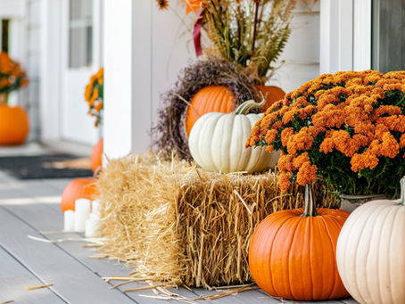 Custom fall front porch decorated with heirloom pumpkins, white pumpkins, orange mums, hay bales, and seasonal décor by Pumpkin City Designs.