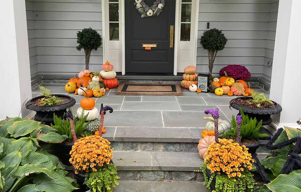 Custom fall porch design with layered pumpkins and colorful mums by Pumpkin City Porches