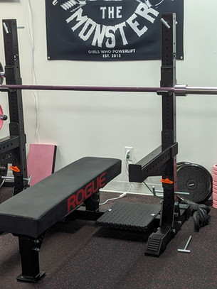 Rogue competition bench press rack, Texas bench bar, spotter platforms, adjustable heavy duty safeties.