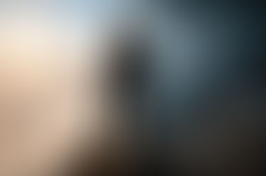 Homem em pé na beira de um penhasco rochoso, olhando para o horizonte dividido entre luz e tempestade, com montanhas ao fundo e nuvens densas abaixo, simbolizando confronto entre caminhos e escolhas.