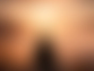 Homem solitário visto de costas, sentado à beira de um penhasco sob um céu nublado, observando um vale coberto por nuvens densas, em atmosfera fria e silenciosa.