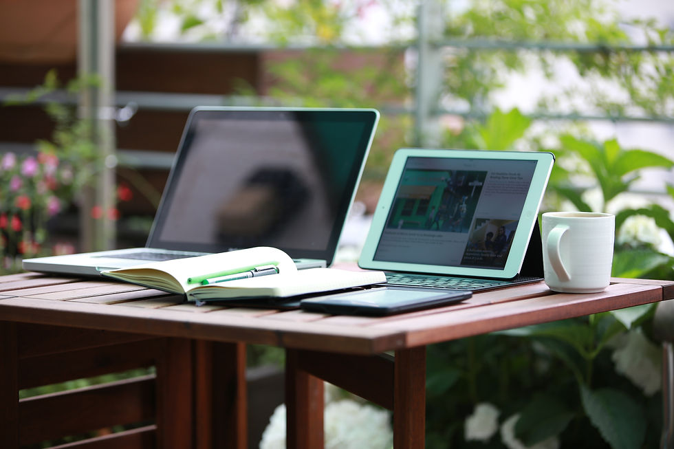 A laptop, iPad and a notebook on a table
