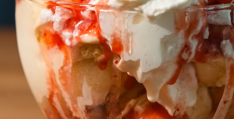 A berry pavlova ice cream sundae topped with whipped cream, fresh strawberries and mint.