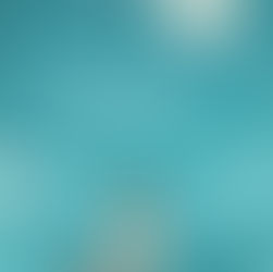 Una donna di spalle sulla riva di fronte al mare con una valigia accanto a sè