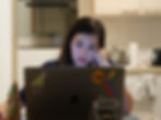 A woman works late into the night on her laptop in a cozy kitchen setting, her focus intense amidst the quiet surroundings.