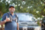 Man with chest rig smiles next to dark SUV