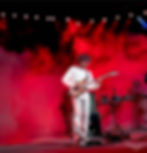 Musician playing guitar under red stage lights