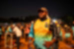 Man in cap and colorful shirt holding water bottle at event.