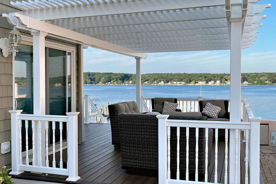 White pergola with seating overlooking a lake and trees on a sunny day