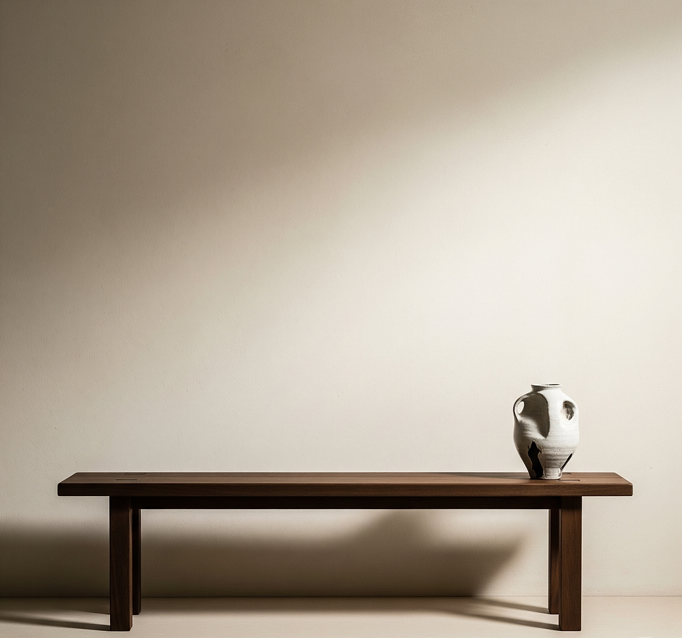 A white ceramic vase sits on a minimalist wooden bench against a beige wall. The scene is calm and uncluttered with soft lighting. It illustrates 'negative space'.
