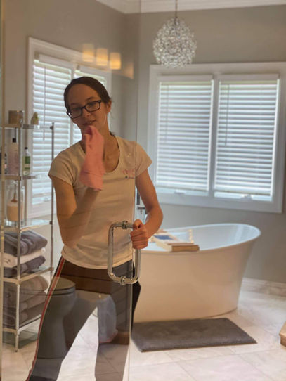 Woman cleaning a glass shower door with a cloth
