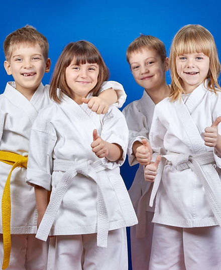 4 children ages 8-10 wearing white martial arts uniforms being friendly