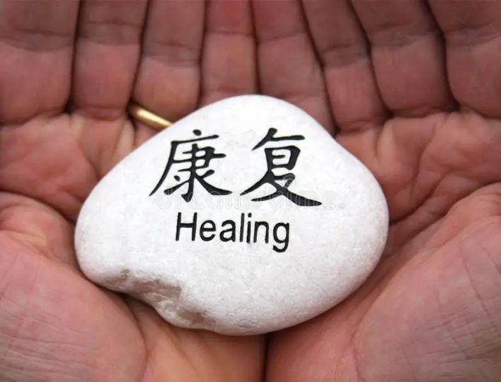 Hands gently cradle a stone with the word "Healing" inscribed, symbolizing care and restoration.