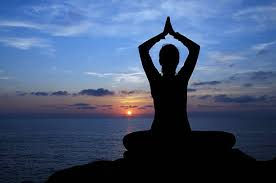 A person practices yoga by the sea at sunrise, embracing tranquility and inner peace.