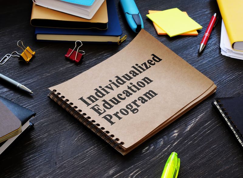 A brown book on a table with the words Individualized Education Plan on the cover