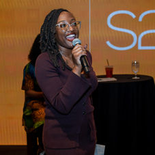 Woman speaking into a microphone at an S2S event