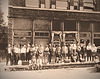 Historic photo of men gathered outside an old business building