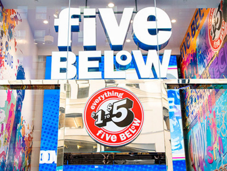 Five Below store entrance featuring large illuminated logo signage, a red circular badge reading "everything $1 to $5," and colorful graphic panels on either side of the entrance