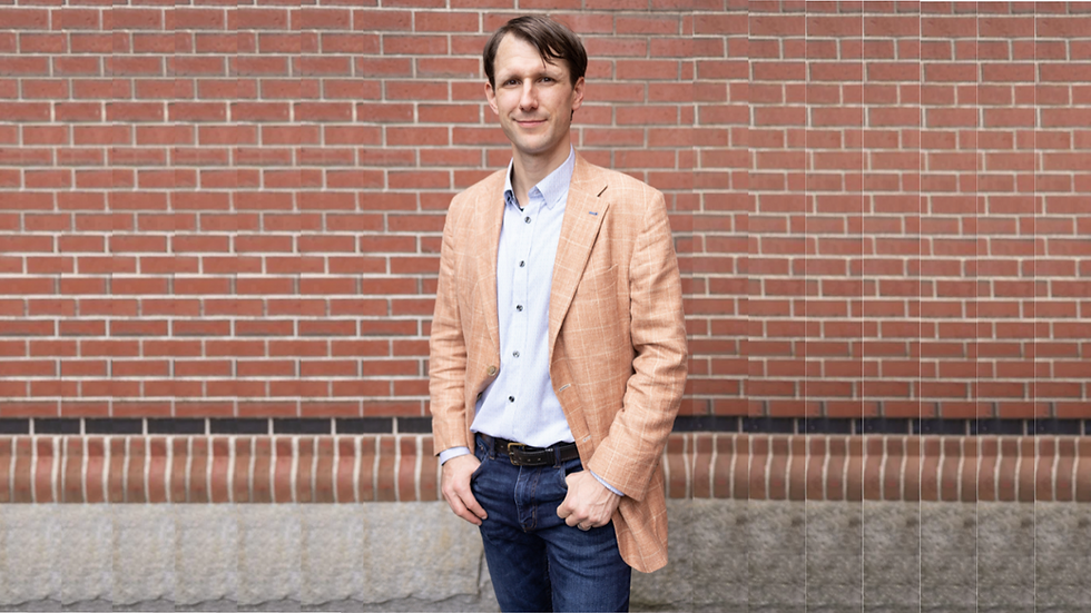 Rich Schnitzel, VP Business Development at KRCrossing, standing confidently against brick wall wearing tan blazer and blue shirt