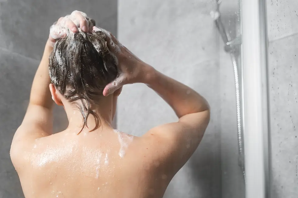 A woman washing her hair with shampoo in the shower