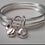 Thumbnail: The Birthday Bangle. A set of six silver bangles with a gold heart and birthston