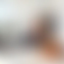 Plumber sits on kitchen floor, inspecting sink pipes with an orange tablet. Tools in a bag, bright room with glass doors, calm mood.