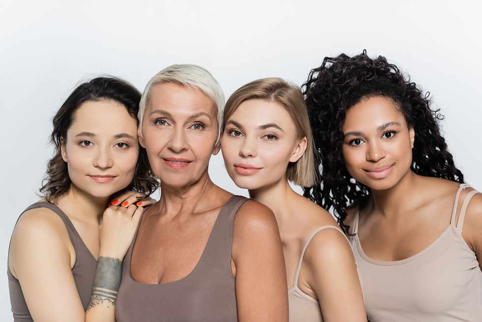 Four diverse women smiling close together, embracing, and looking at the camera