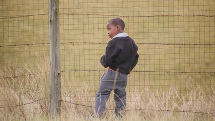 Babheke SPS in the Eastern Cape, South Africa, little boy relieving himself by the school fence