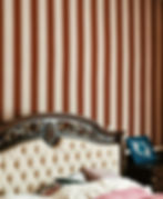 Elegant tufted headboard against striped wallpaper, decorated with gold accents.