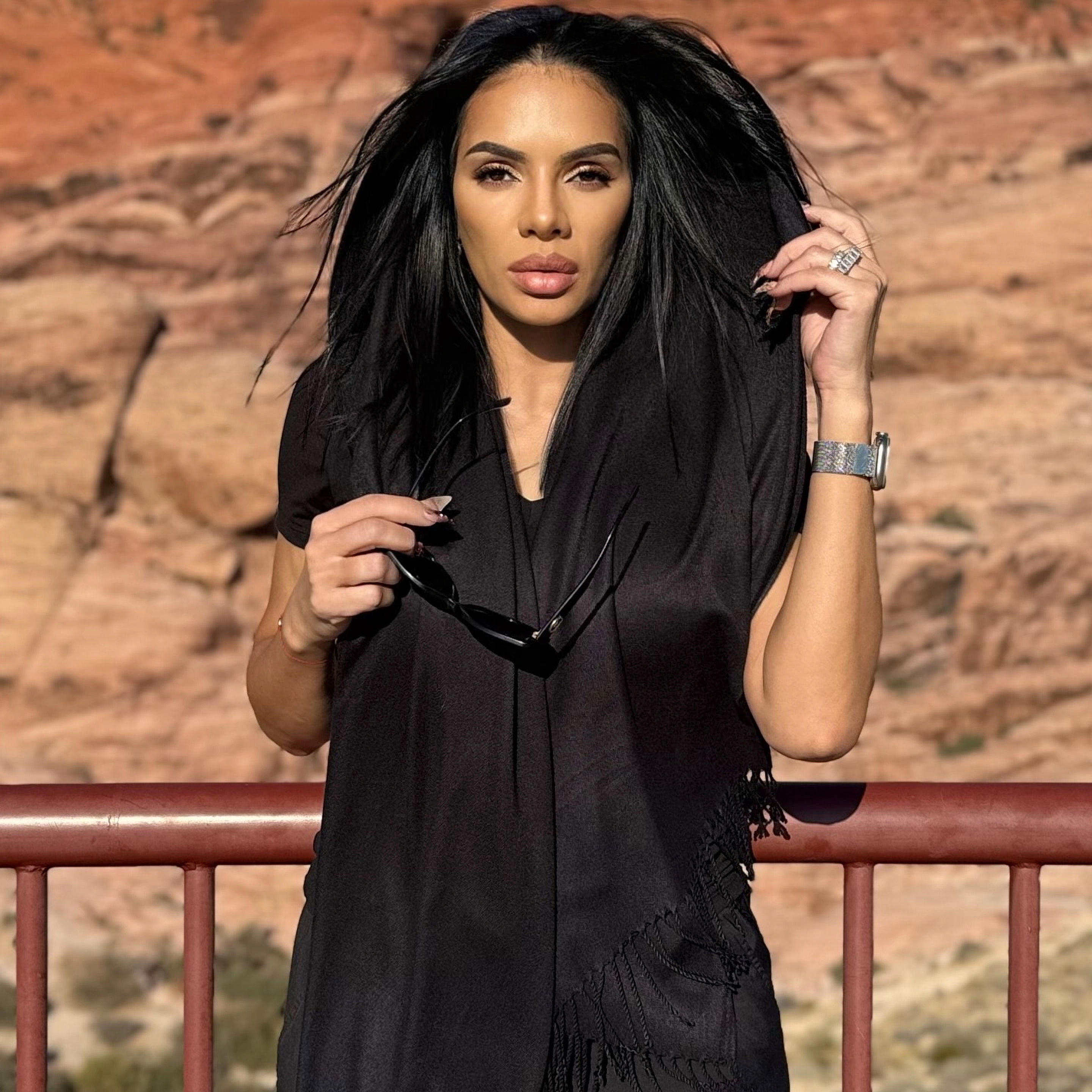 Woman in black attire posing against desert canyon views.